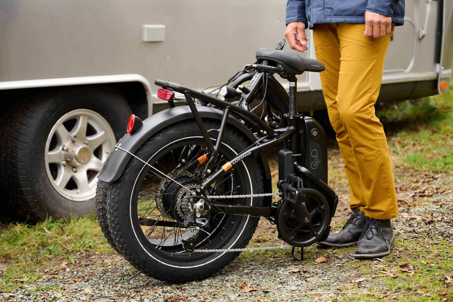Person standing next to a folded RadExpand 5 electric folding bike